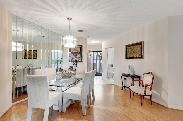 dining area featuring a textured ceiling, light hardwood / wood-style flooring, and a notable chandelier