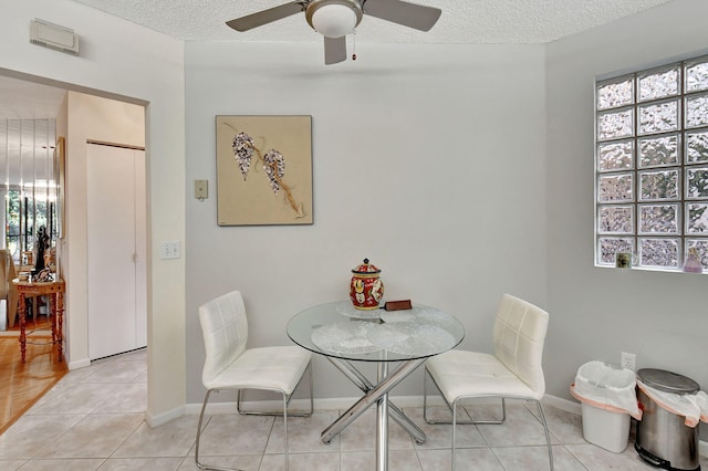 tiled dining room featuring ceiling fan, plenty of natural light, and a textured ceiling