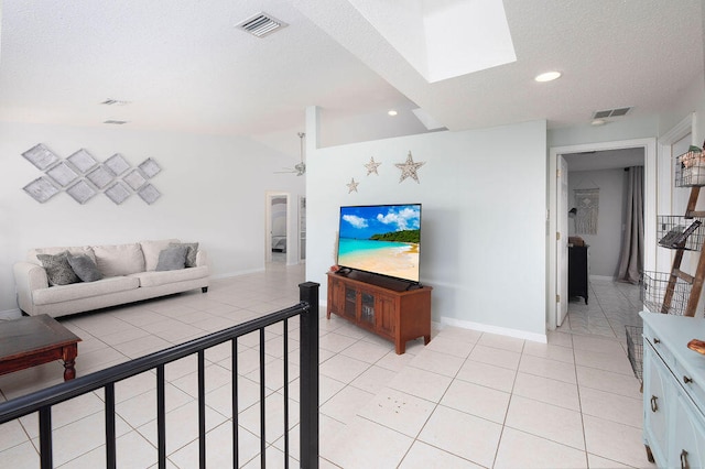 tiled living room featuring ceiling fan and lofted ceiling with skylight