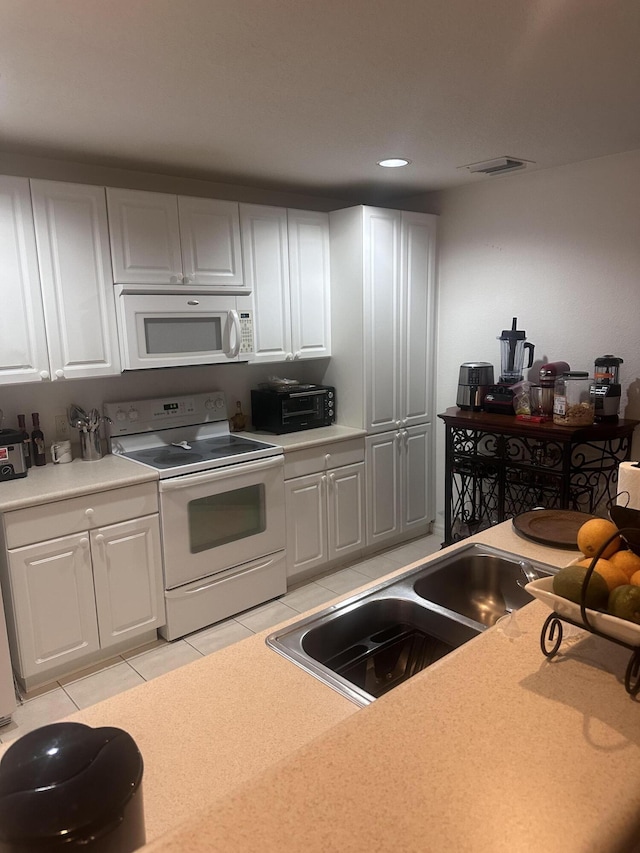 kitchen with white cabinets, white appliances, light tile patterned flooring, and sink