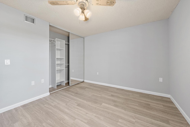 unfurnished bedroom with a closet, a textured ceiling, light wood-type flooring, and ceiling fan