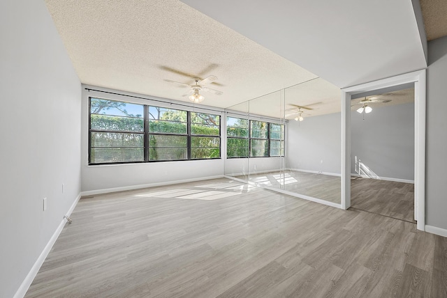 unfurnished bedroom featuring a closet, a textured ceiling, light wood-type flooring, and ceiling fan