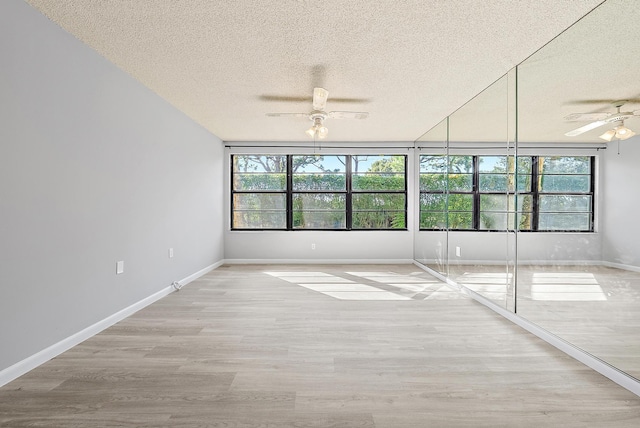 unfurnished room featuring a textured ceiling, light wood-type flooring, and ceiling fan