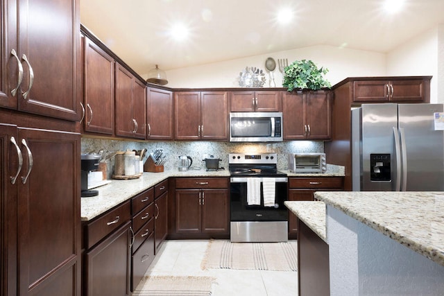 kitchen featuring light tile patterned floors, appliances with stainless steel finishes, backsplash, vaulted ceiling, and light stone counters