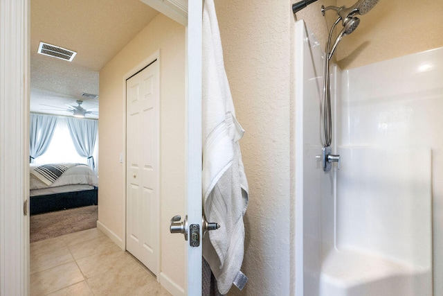 bathroom featuring a textured ceiling, ceiling fan, a shower, and tile patterned floors