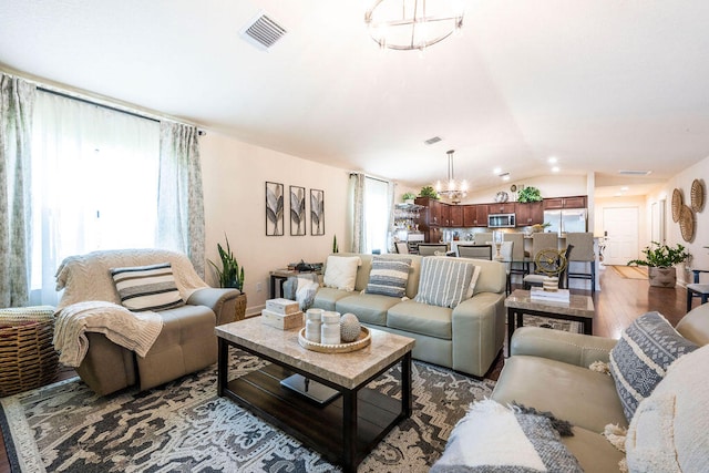 living room with an inviting chandelier, hardwood / wood-style floors, and vaulted ceiling