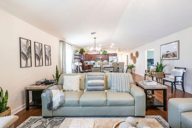 living room with dark hardwood / wood-style flooring, a notable chandelier, and vaulted ceiling