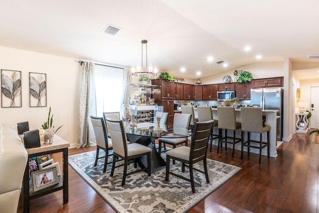 dining space with dark wood-type flooring, vaulted ceiling, and an inviting chandelier