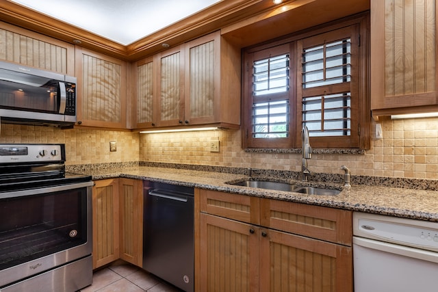 kitchen with sink, stainless steel appliances, tasteful backsplash, light stone counters, and light tile patterned floors