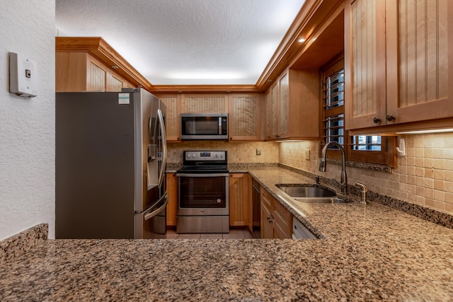 kitchen with backsplash, sink, a textured ceiling, stone countertops, and stainless steel appliances