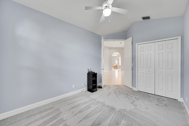 unfurnished bedroom with a closet, light carpet, lofted ceiling, and ceiling fan