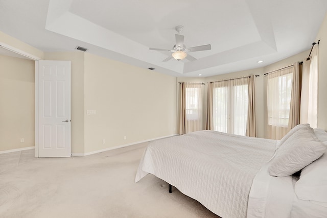 carpeted bedroom with ceiling fan and a tray ceiling