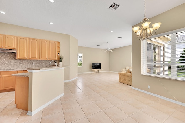 kitchen with light brown cabinetry, ventilation hood, hanging light fixtures, and tasteful backsplash