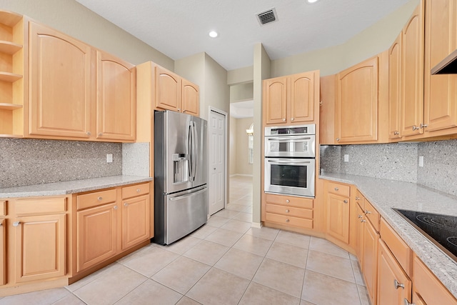 kitchen with light brown cabinets, tasteful backsplash, and stainless steel appliances