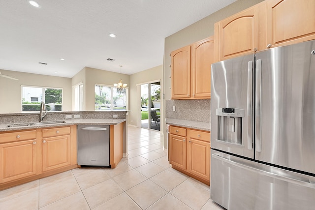 kitchen featuring light brown cabinetry, sink, stainless steel appliances, light stone counters, and an inviting chandelier