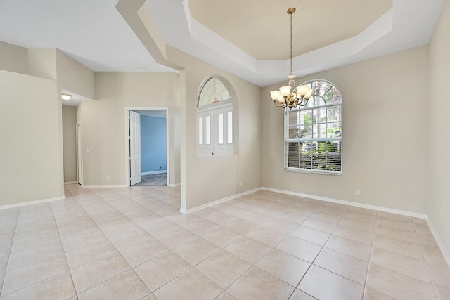 empty room featuring a notable chandelier, light tile patterned floors, and a raised ceiling