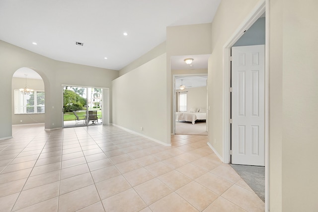 spare room with ceiling fan with notable chandelier and light tile patterned floors