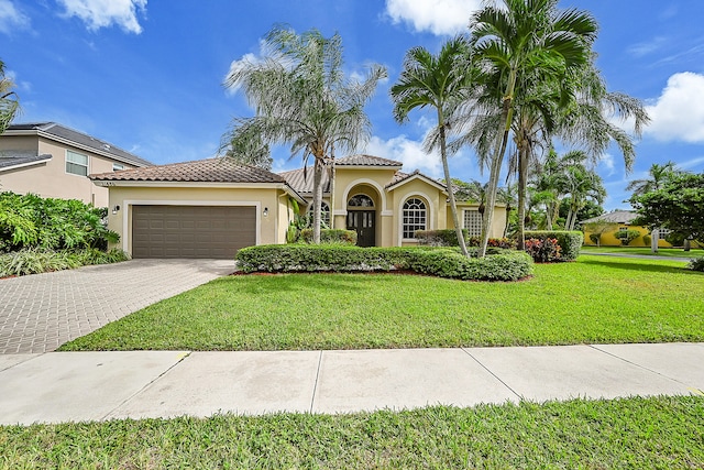 mediterranean / spanish home featuring a front yard and a garage