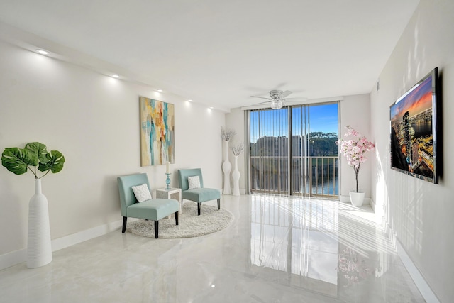 sitting room featuring a wall of windows and ceiling fan