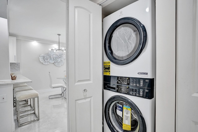 washroom featuring stacked washer / dryer and a notable chandelier