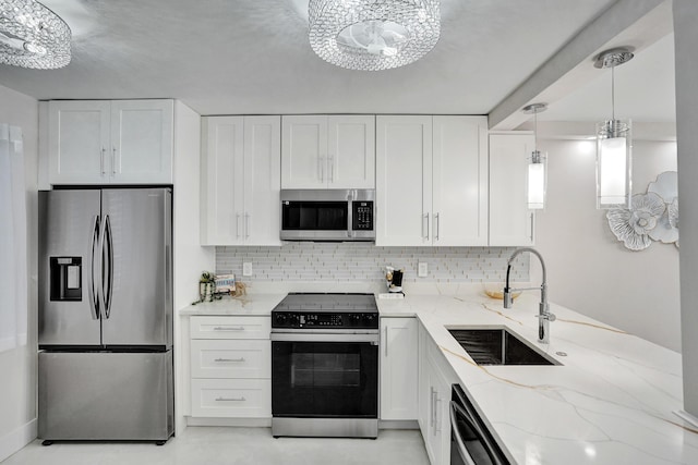 kitchen featuring white cabinets, stainless steel appliances, light stone counters, and a sink