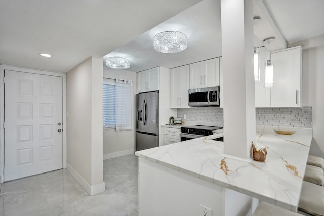 kitchen with stainless steel appliances, hanging light fixtures, white cabinets, and light stone counters