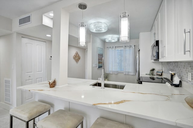 kitchen featuring sink, decorative light fixtures, light stone countertops, and kitchen peninsula