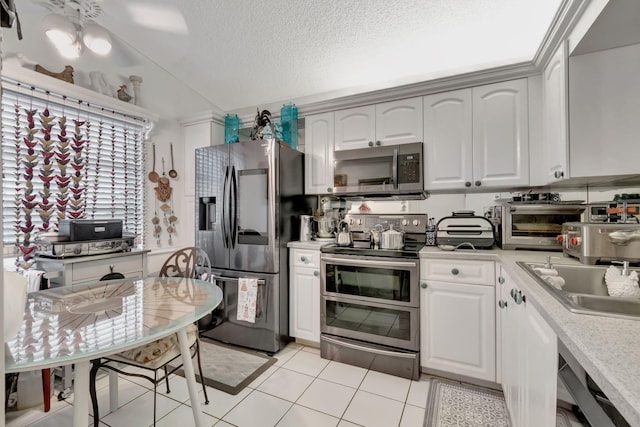 kitchen with stainless steel appliances, light tile patterned flooring, white cabinetry, a textured ceiling, and ceiling fan