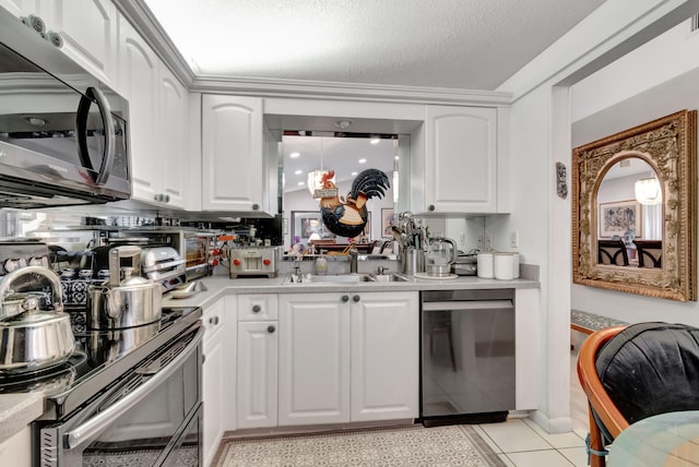 kitchen featuring stainless steel appliances, sink, light tile patterned flooring, white cabinets, and a textured ceiling