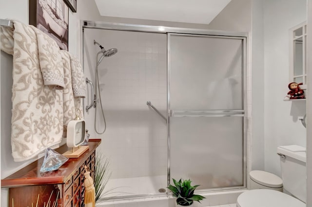 bathroom featuring a shower with door and toilet