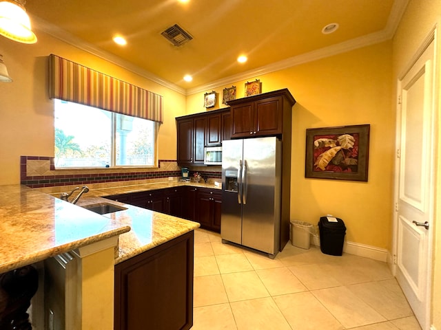 kitchen with backsplash, light stone counters, ornamental molding, dark brown cabinetry, and stainless steel appliances