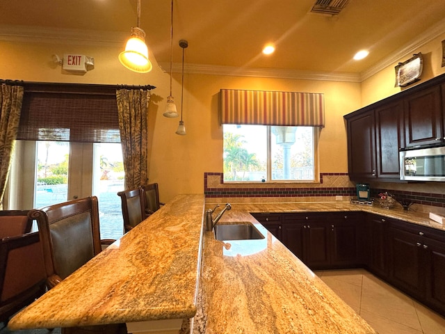 kitchen with decorative backsplash, light stone countertops, a wealth of natural light, and sink