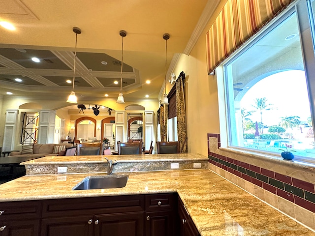 kitchen featuring sink, coffered ceiling, crown molding, decorative light fixtures, and dark brown cabinets