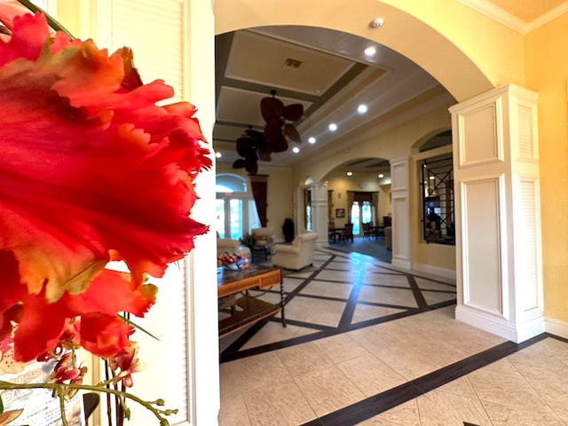 hallway featuring ornate columns, crown molding, and light tile patterned floors