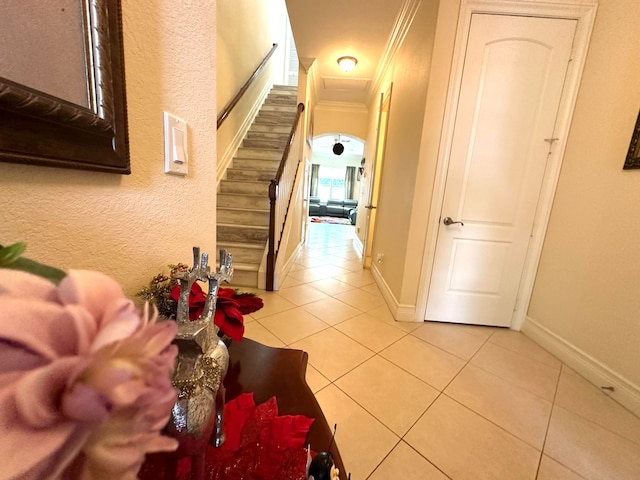 hall featuring light tile patterned floors and crown molding