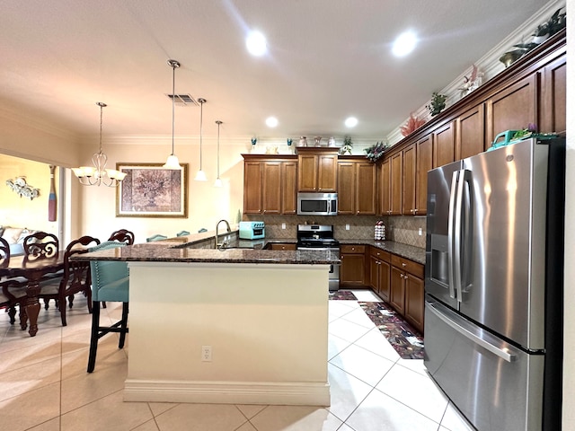 kitchen featuring pendant lighting, ornamental molding, appliances with stainless steel finishes, a notable chandelier, and a kitchen bar