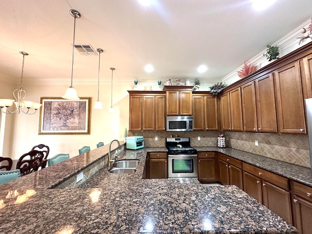 kitchen featuring sink, a notable chandelier, crown molding, pendant lighting, and appliances with stainless steel finishes