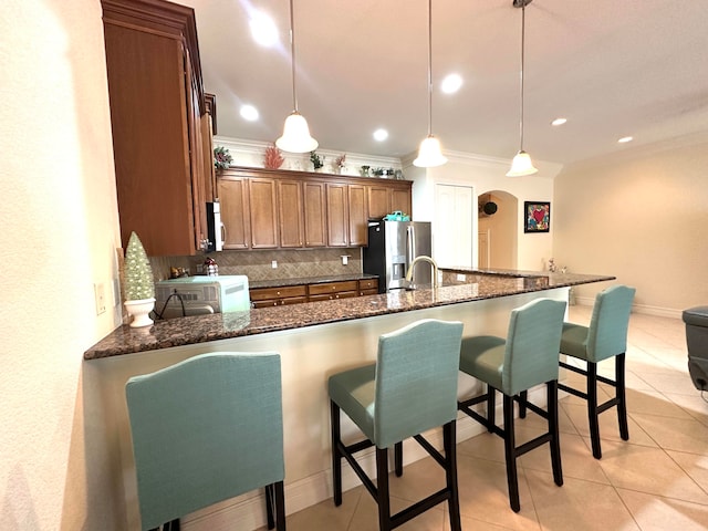 kitchen with pendant lighting, a breakfast bar, dark stone countertops, appliances with stainless steel finishes, and tasteful backsplash