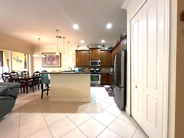 kitchen with pendant lighting, decorative backsplash, ornamental molding, appliances with stainless steel finishes, and a breakfast bar area