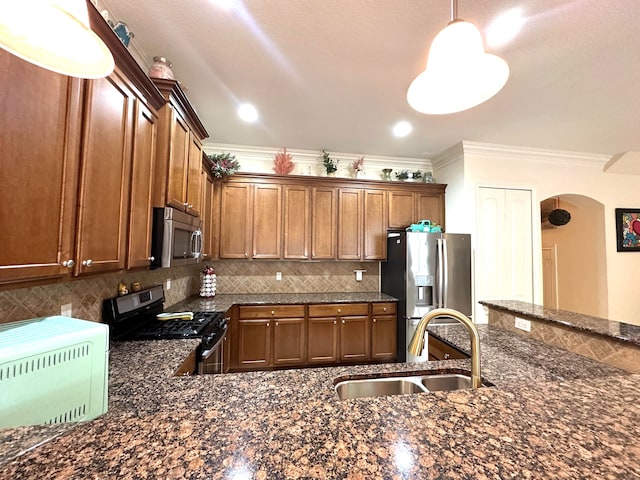 kitchen with pendant lighting, crown molding, sink, decorative backsplash, and stainless steel appliances