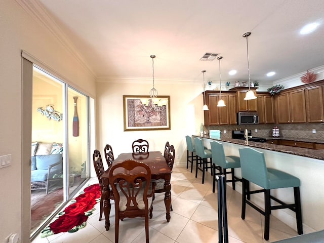 dining room featuring crown molding, light tile patterned floors, and a notable chandelier