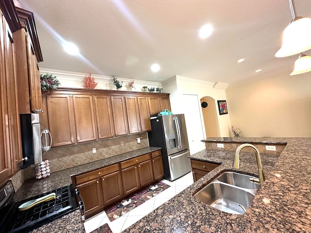 kitchen featuring sink, hanging light fixtures, crown molding, dark stone counters, and appliances with stainless steel finishes