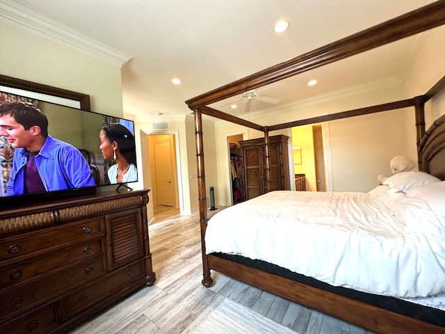 bedroom featuring connected bathroom, light hardwood / wood-style flooring, and crown molding