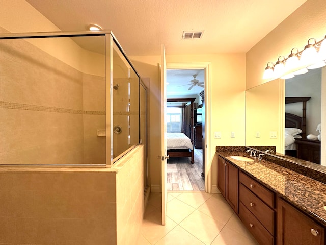 bathroom with tile patterned floors, vanity, a textured ceiling, ceiling fan, and a shower