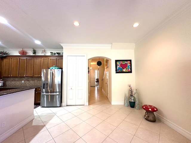 kitchen with backsplash, crown molding, light tile patterned floors, and stainless steel refrigerator with ice dispenser