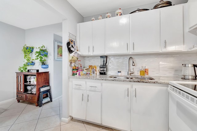 kitchen featuring decorative backsplash, sink, light stone countertops, light tile patterned floors, and white cabinets