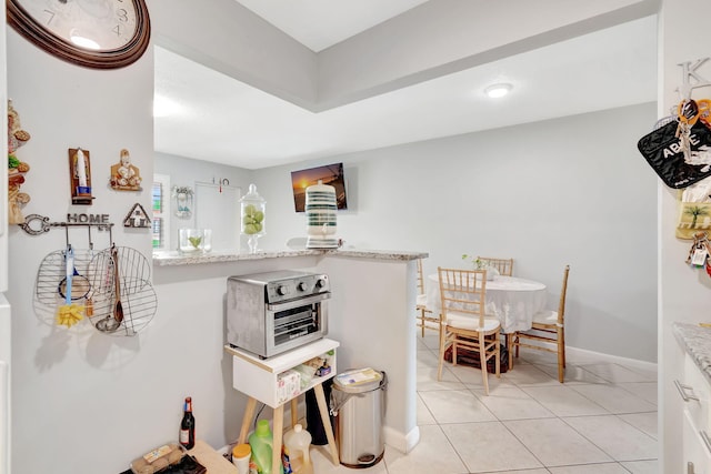 kitchen with light stone counters, light tile patterned flooring, and white cabinets