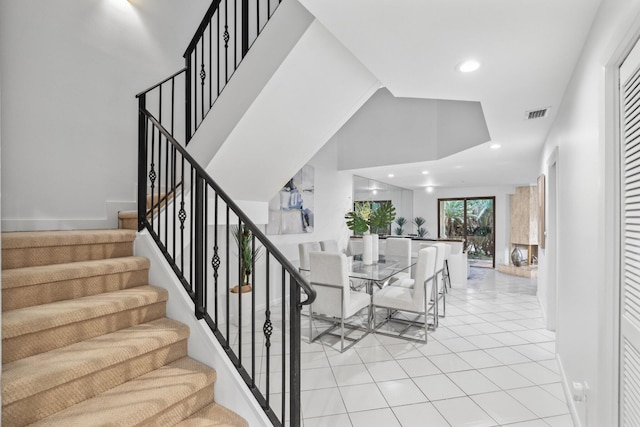 stairs featuring recessed lighting, a towering ceiling, visible vents, and tile patterned floors