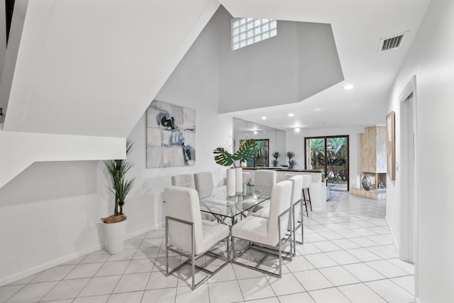 dining space featuring light tile patterned floors, baseboards, visible vents, a high ceiling, and recessed lighting