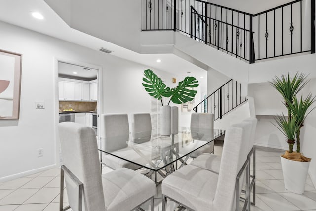 dining space featuring light tile patterned floors, baseboards, visible vents, a towering ceiling, and recessed lighting